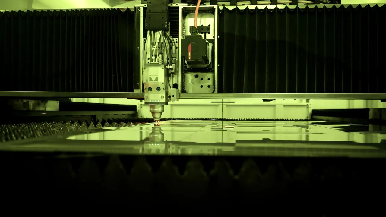 Interior de la máquina de corte láser de IMGAR, con el cabezal sobre la chapa bajo la luz verde de protección